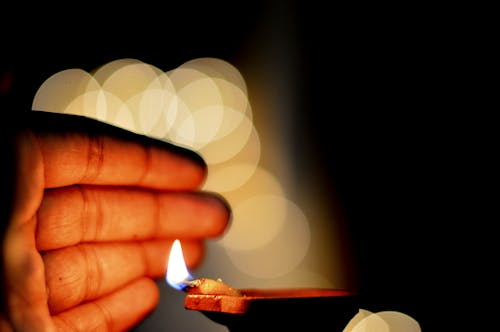 Free Hand Close to a Lit Diya Stock Photo