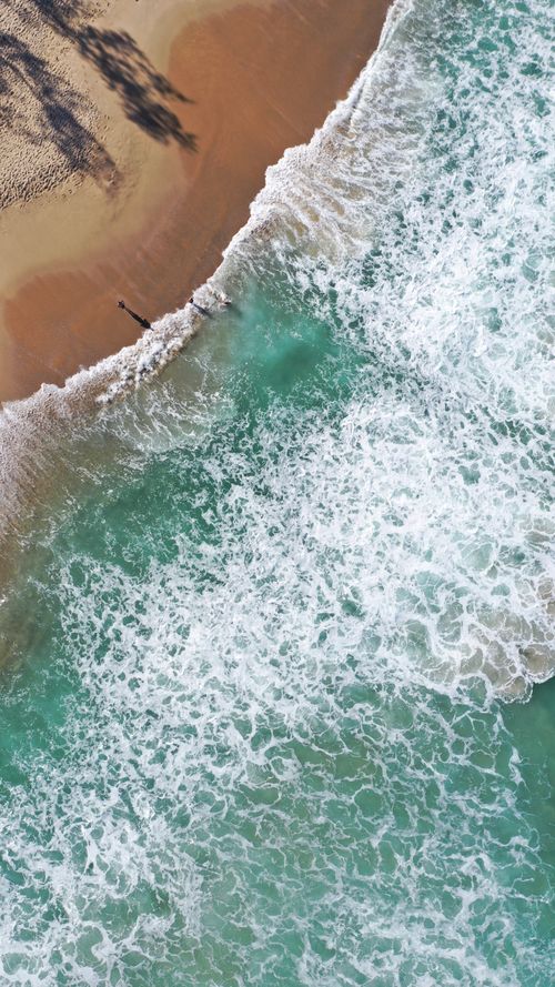 Free Stunning aerial shot of turquoise ocean waves meeting a sandy beach in Campeche, Brazil. Stock Photo
