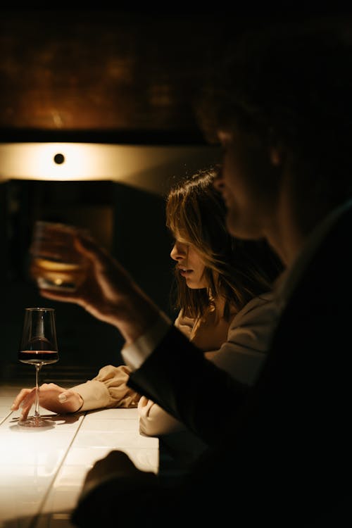 透明なワイングラスを保持している黒の長袖シャツの女性