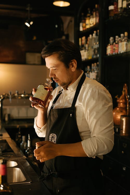 Man in White Dress Shirt Holding Glass Bottle