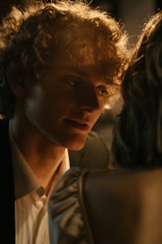 A man whispering to a woman in a dimly lit restaurant setting, creating an intimate ambiance.