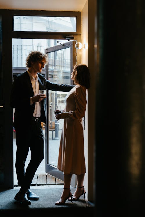 Man in Black Suit Standing Beside Woman in White Long Sleeve Shirt