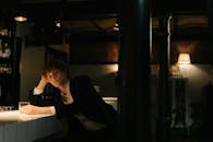 一个穿着黑色西装的年轻人独自坐在酒吧里，陷入沉思