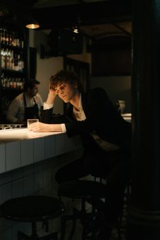 酒吧里的男人喝着一杯酒，流露出沉思和内省的情绪