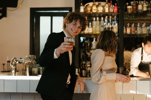 Free Man and woman enjoying evening drinks at a stylish bar, engaged in cheerful conversation. Stock Photo