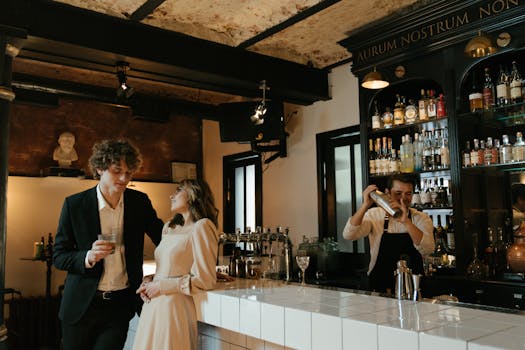 A romantic couple enjoys drinks at an elegant bar while a bartender prepares cocktails.