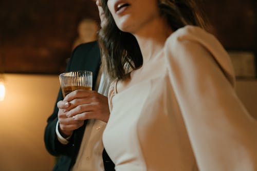 Woman in White Long Sleeve Shirt Holding Drinking Glass
