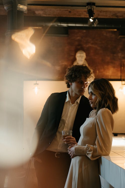 Man in Black Suit Kissing Woman in Brown Coat