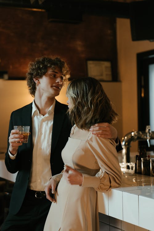 Woman in White Blazer Holding Man in Black Suit