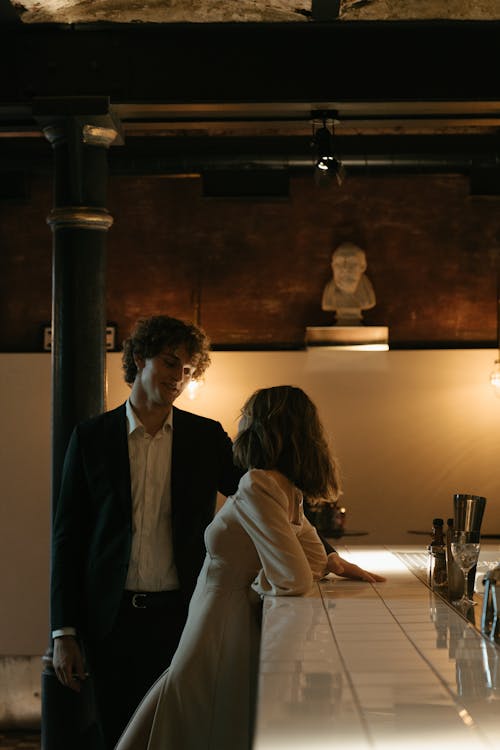 Man in Black Suit Jacket Sitting Beside Woman in White Long Sleeve Shirt