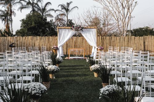 Free Beautiful outdoor wedding ceremony setup with white chairs and floral decorations. Stock Photo