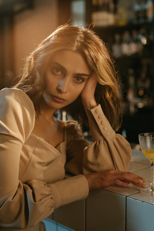 Woman in Brown Long Sleeve Shirt Holding Clear Drinking Glass