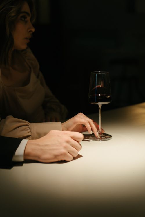 Free A man and woman enjoying wine in a dimly lit bar, highlighting elegance and intimacy. Stock Photo