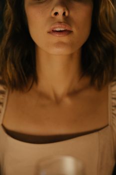 温暖的灯光下，特写女人的领口和嘴唇，展现优雅与美丽