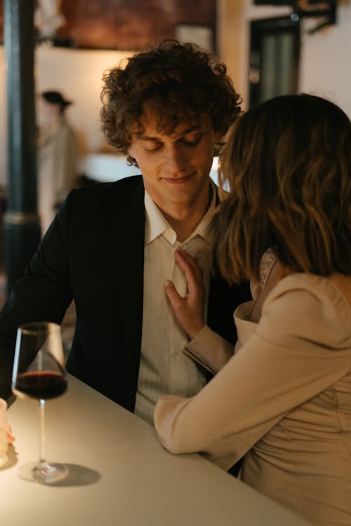 Woman in Beige Coat Sitting Beside Man in Black Suit