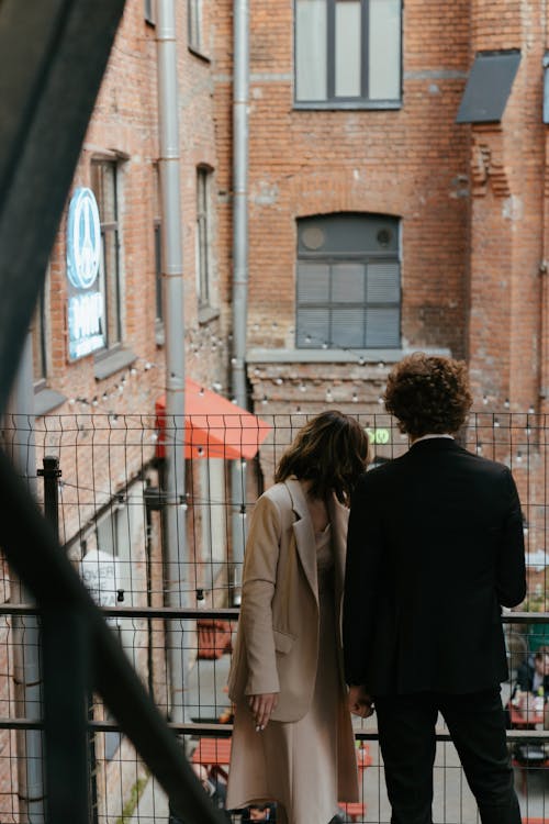 Woman in Beige Coat Standing Beside Man in Black Suit