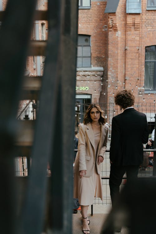 Woman in Brown Coat Standing Near Man in Black Suit