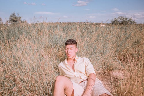 Man in Beige Dress Shirt Lying on Brown Grass Field