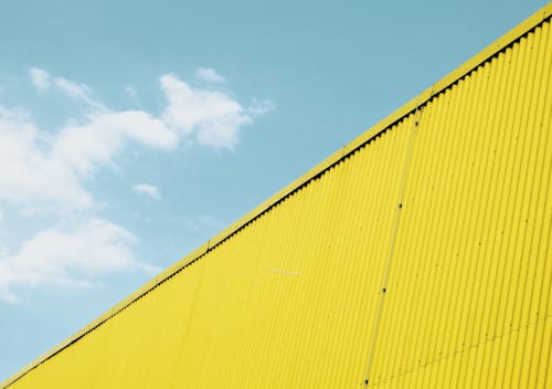 Yellow Wall Made of Corrugated Steel Against the Blue Sky