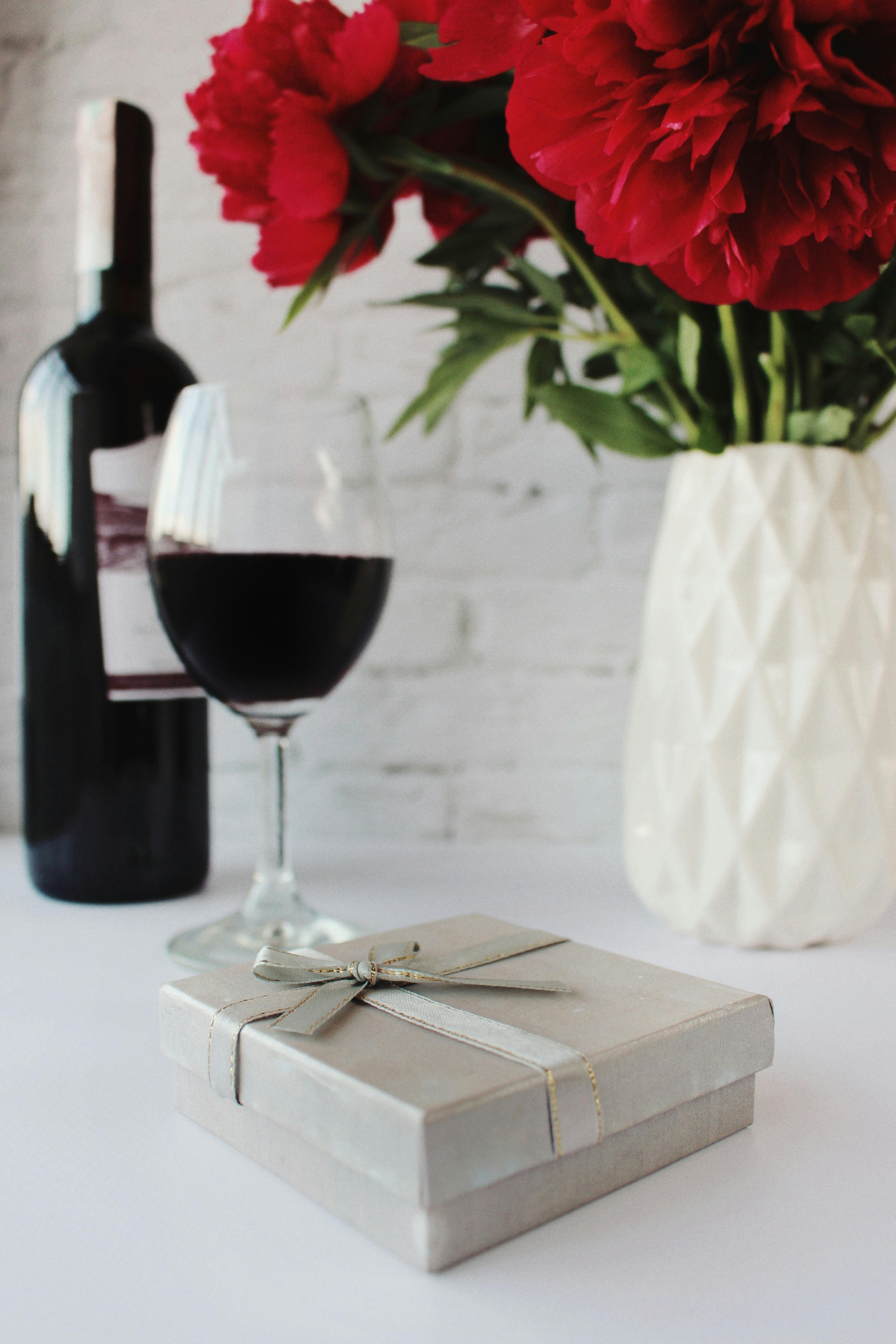 red rose in clear wine glass beside white ceramic vase