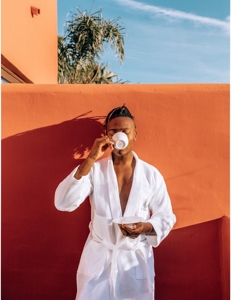 Man Drinking Coffee Near Orange Wall