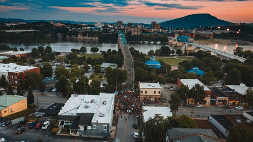 Free Aerial view of anonymous crowd of people on roadway between buildings and river under cloudy sky at sunset during strike Stock Photo