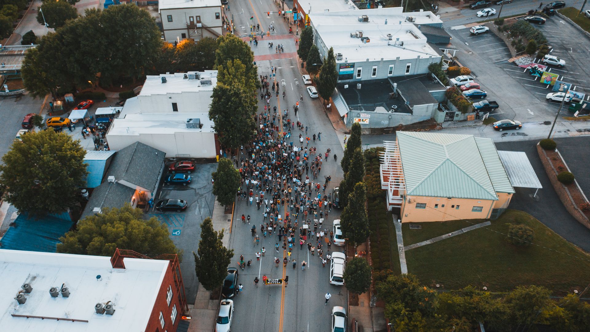 Aerial view of unrecognizable people on roadway between houses and trees during strike in town