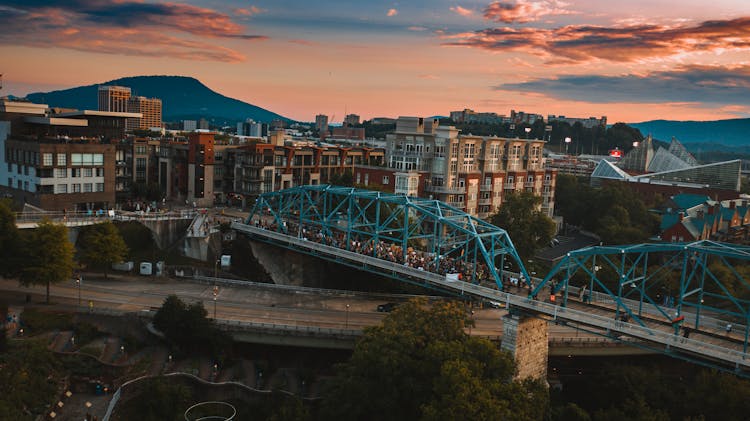 Anonymous People On Old Bridge Over River At Sunset