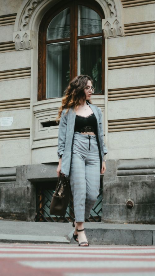 Free Low angle full body of confident stylish female in suit and high heels crossing road on street near old building and looking away Stock Photo