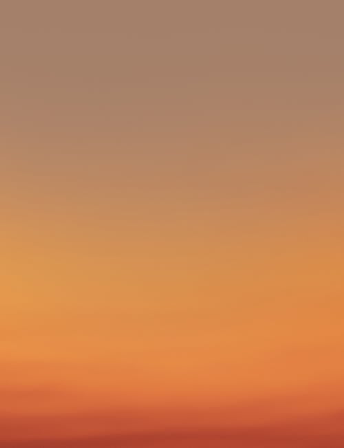 Picturesque view of abstract clear sundown sky background gradient from light yellow to bright orange at evening time in nature