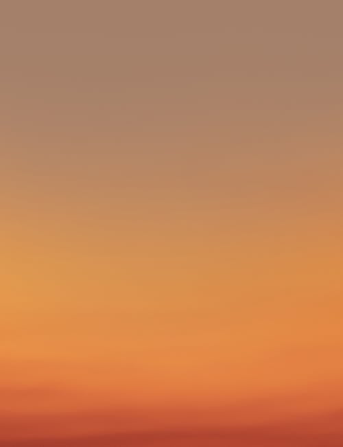 Picturesque view of abstract clear sundown sky background gradient from light yellow to bright orange at evening time in nature