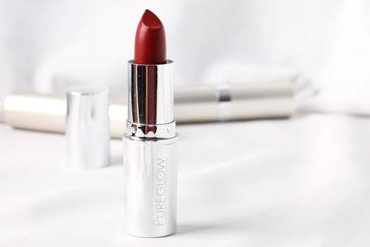 Bold and elegant red lipstick with a silver casing on a soft, blurred white background.