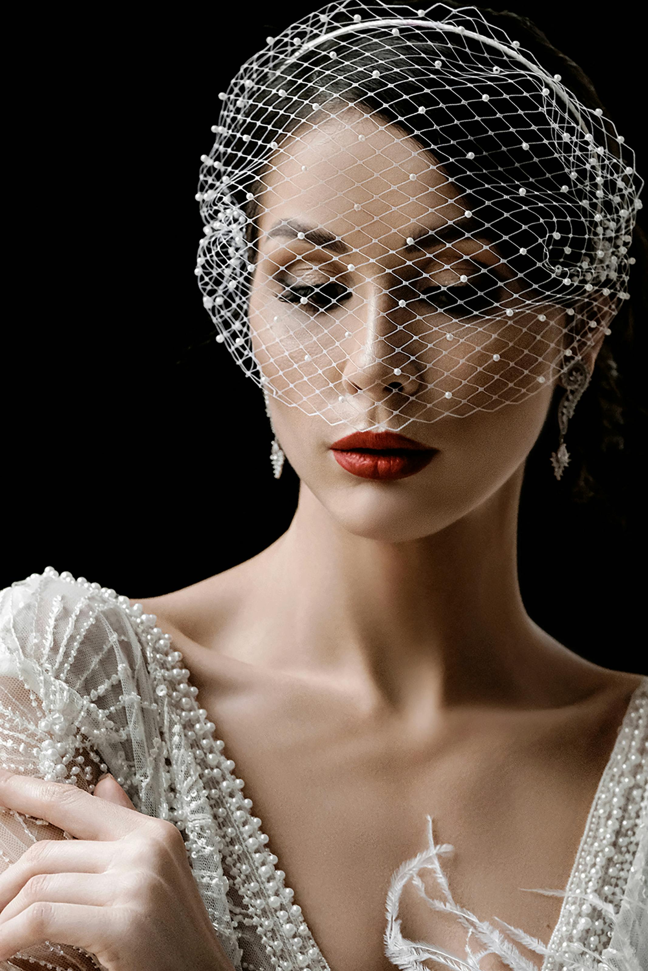 优雅的新娘穿着珍珠装饰的礼服，戴着面纱头饰