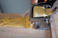 Close-up of pasta maker creating fresh spaghetti in a Roman kitchen.