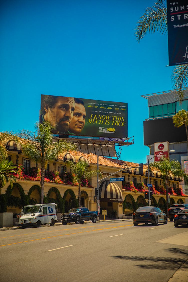 Cars Parked In Front Of Building With Billboards