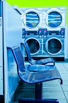 Bright laundromat interior featuring blue chairs and industrial washing machines.