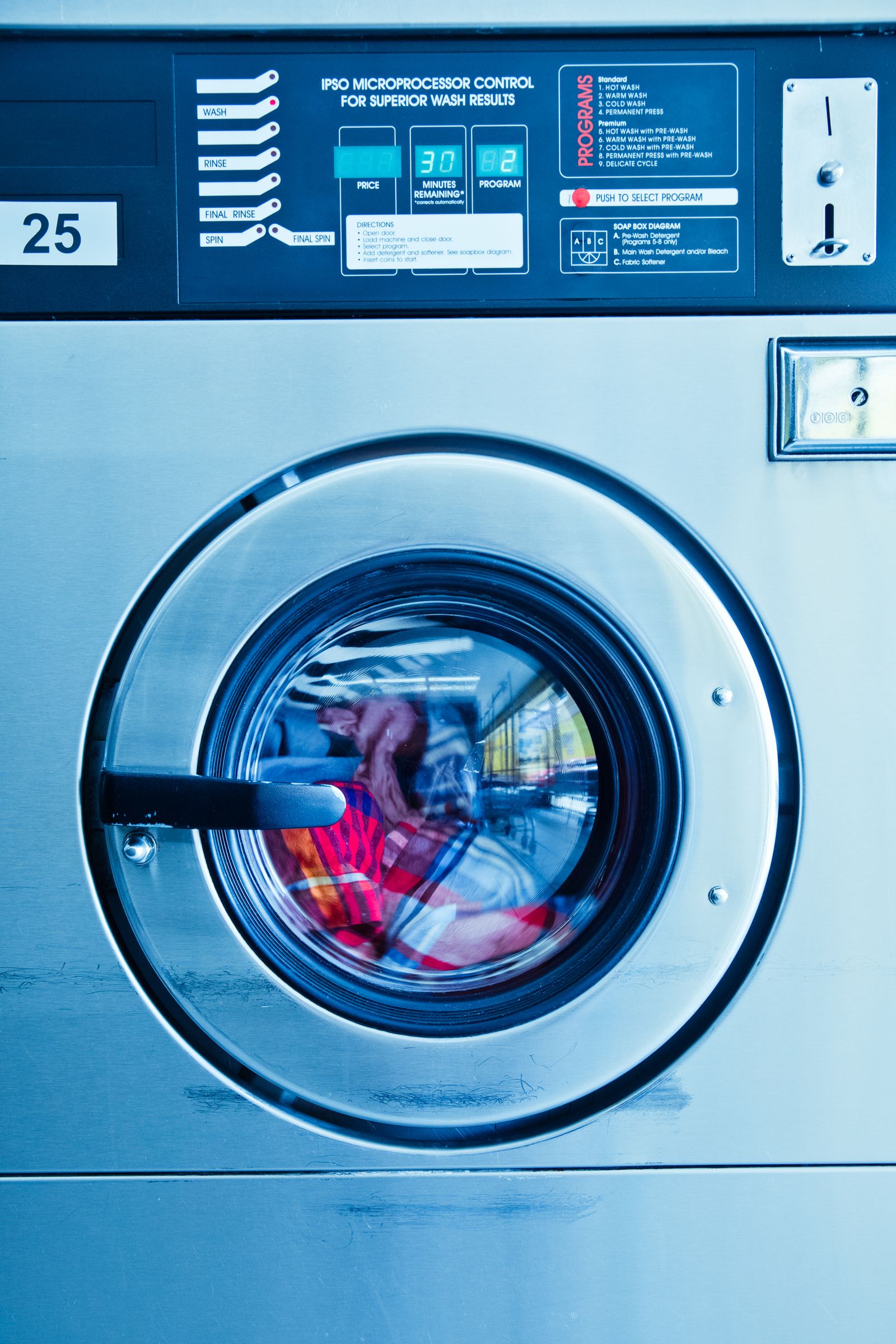 Close-up IPSO washer door with clothes in drum, minutes remaining