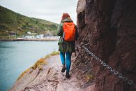 Woman walking on rocky cliff decorated with chain