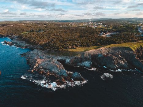 Drone view of rocky isle washed with blue water of turquoise ocean under cloudy sky