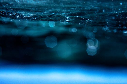 Close-up of ocean water surface creating a mesmerizing bokeh effect with light reflections.