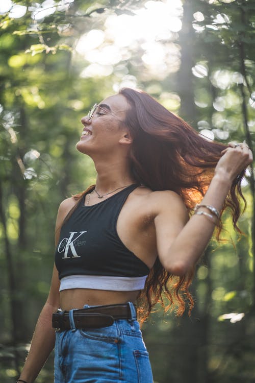 Woman in Black Crop Top and Blue Denim Bottoms Holding Her Hair