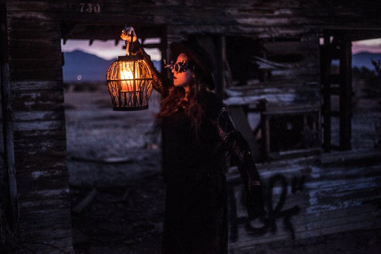 A Woman In A Steampunk Outfit Holding A Lamp