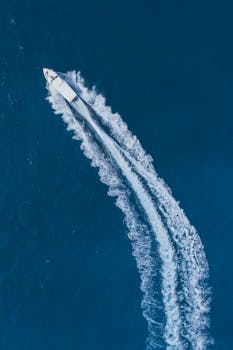 Aerial view of a speedboat creating trails on the clear blue ocean waters of the Maldives.