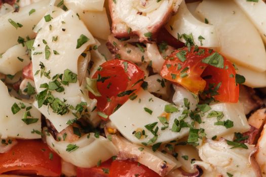 Closeup of delicious healthy food with squids and vegetables under fresh herbs with sauce