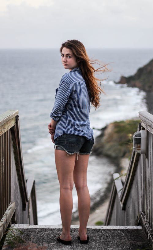 Free A Young Woman Standing by the Seaside Stock Photo
