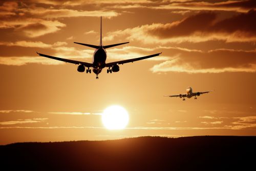 Free Silhouetted airplanes landing against a dramatic sunset sky, capturing the essence of flight. Stock Photo