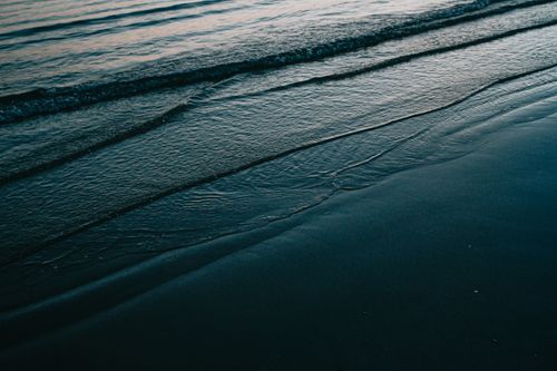Free Gentle ocean waves rolling onto a peaceful beach. Perfect for relaxation scenes. Stock Photo