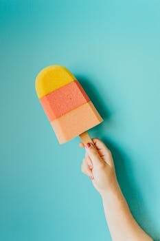 Vibrant multicolored popsicle against a blue backdrop, symbolizing summer refreshment.