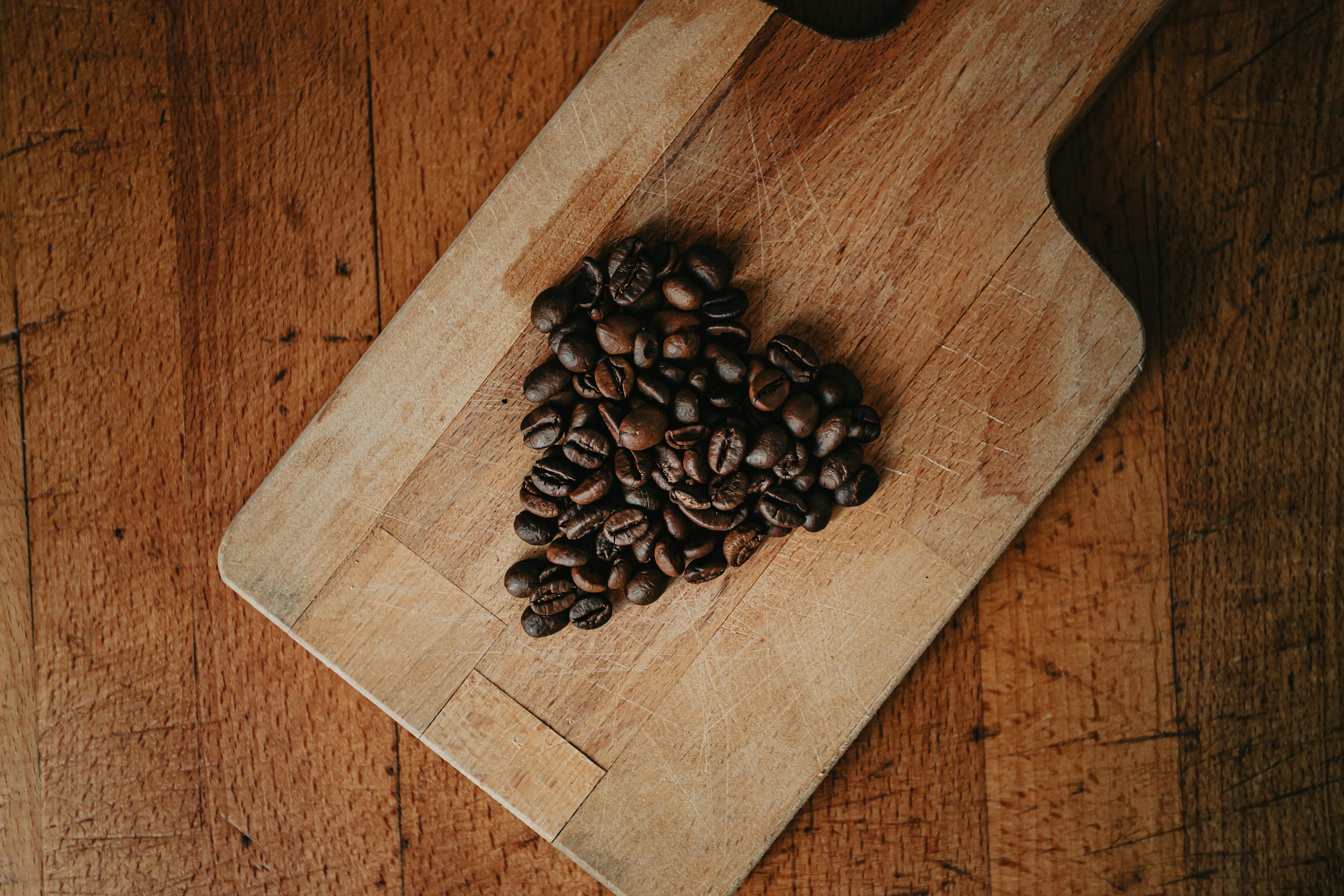 A rustic flat lay of heart-shaped coffee beans on a wooden cutting board, showcasing rich texture.