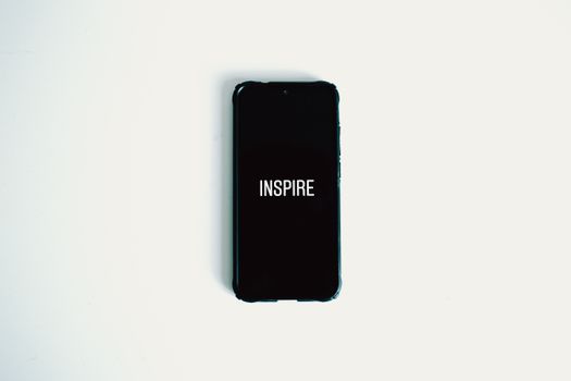 Mobile phone with 'Inspire' text on screen against a white background.